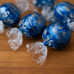 コストコのリンツチョコレートトリュフが木製のテーブルに並んでいる画像。青い金箔包装のリンツリンドールチョコレートが美しく並べられ、背景には柔らかい光が差し込んでいます。